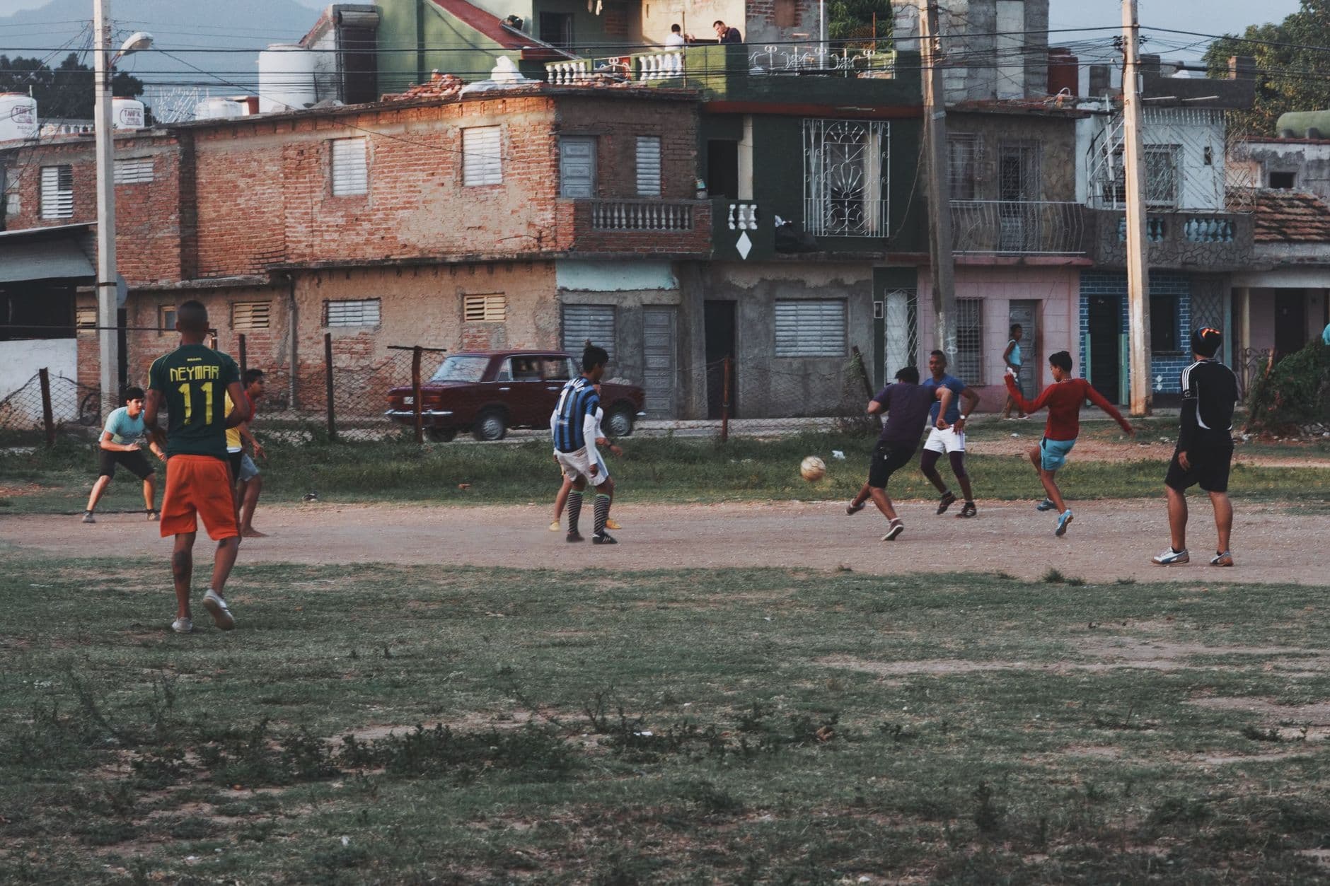 Group of young men playing football on an outdoor field in an urban neighborhood, showcasi