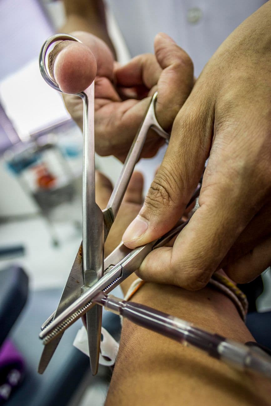 Hands using medical scissors during a procedure, highlighting precision and care in health