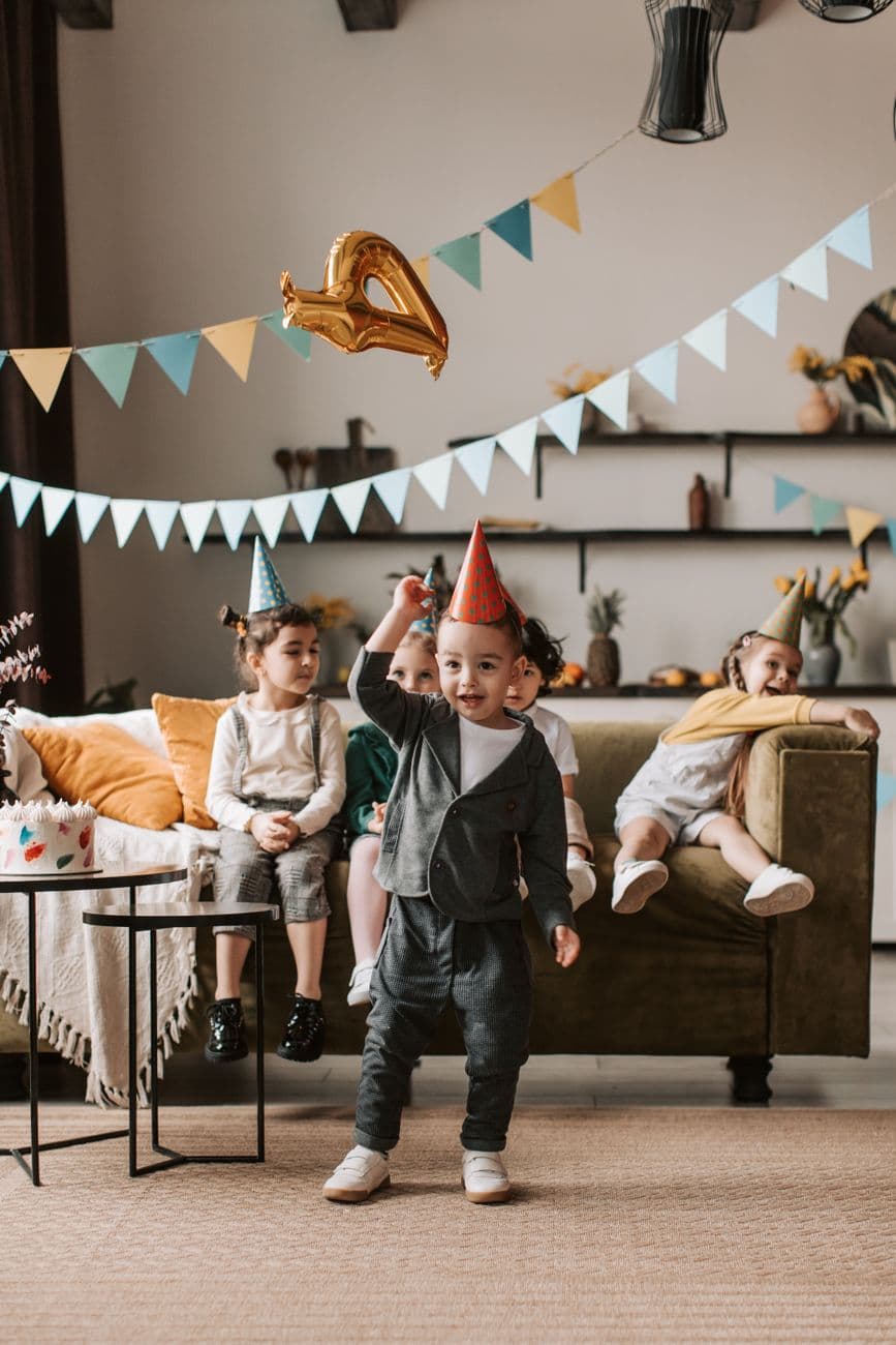Happy children celebrating a birthday at home with balloons and decorations. Joyful indoor