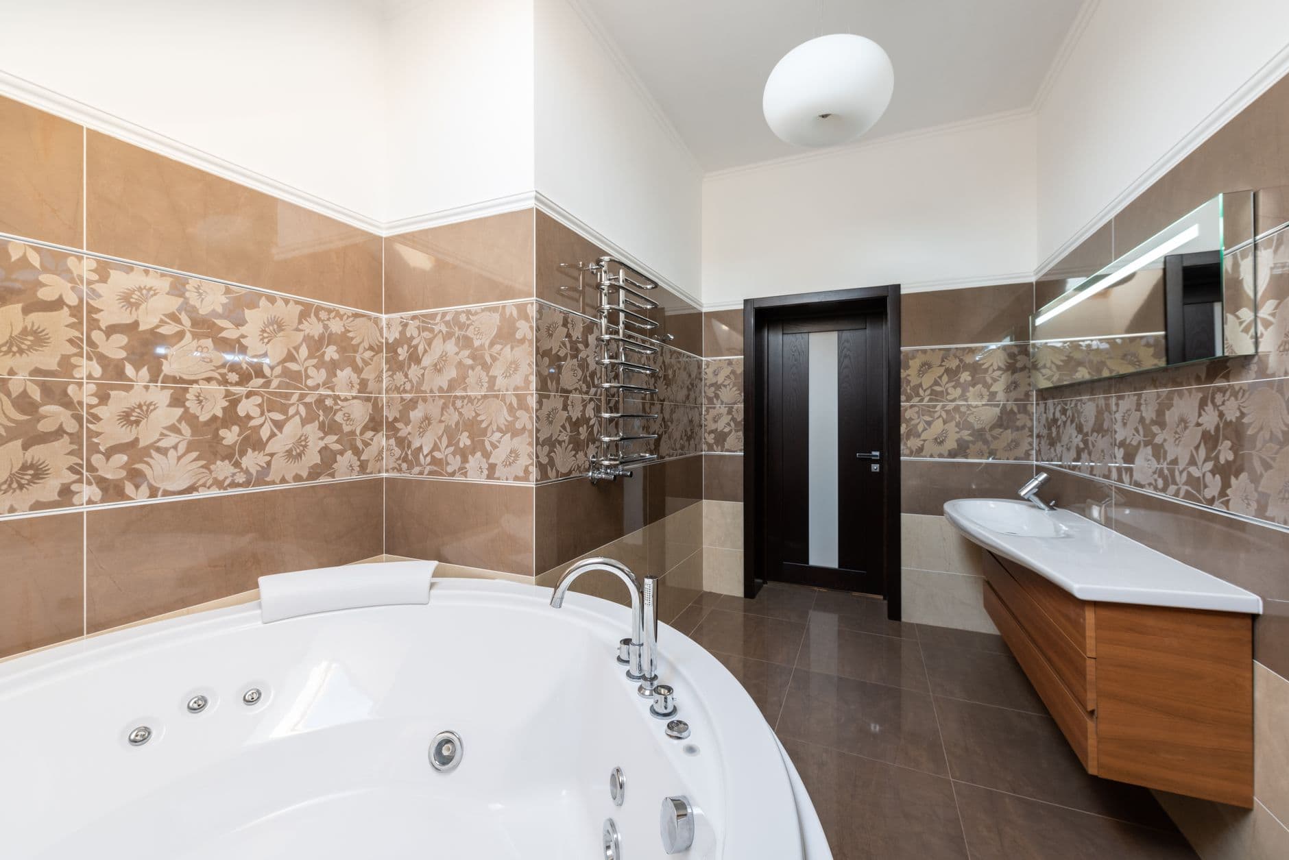 Interior of contemporary bathroom with round ceramic bathtub and sink and wooden cabinet i