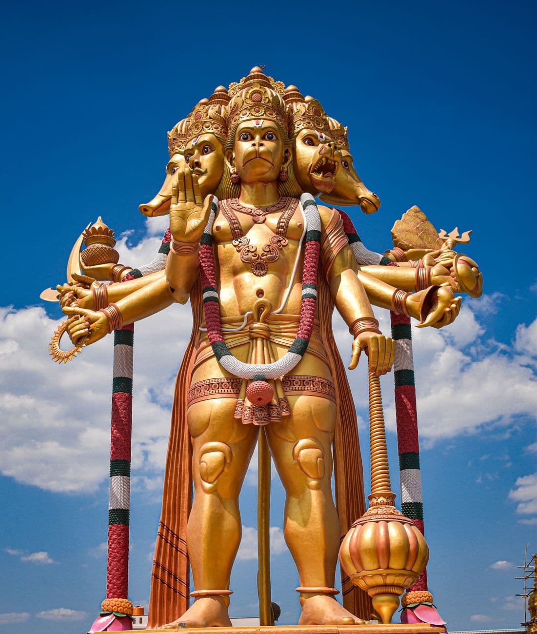 Intricate multi-armed Hindu deity statue with blue sky backdrop, showcasing spiritual and