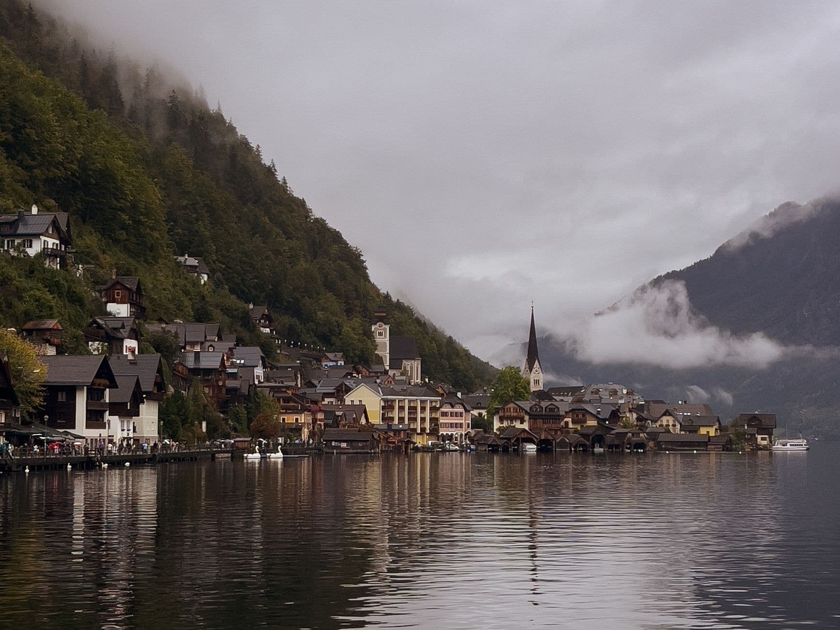 Picturesque village by the lake with misty mountains and charming architecture on a cloudy