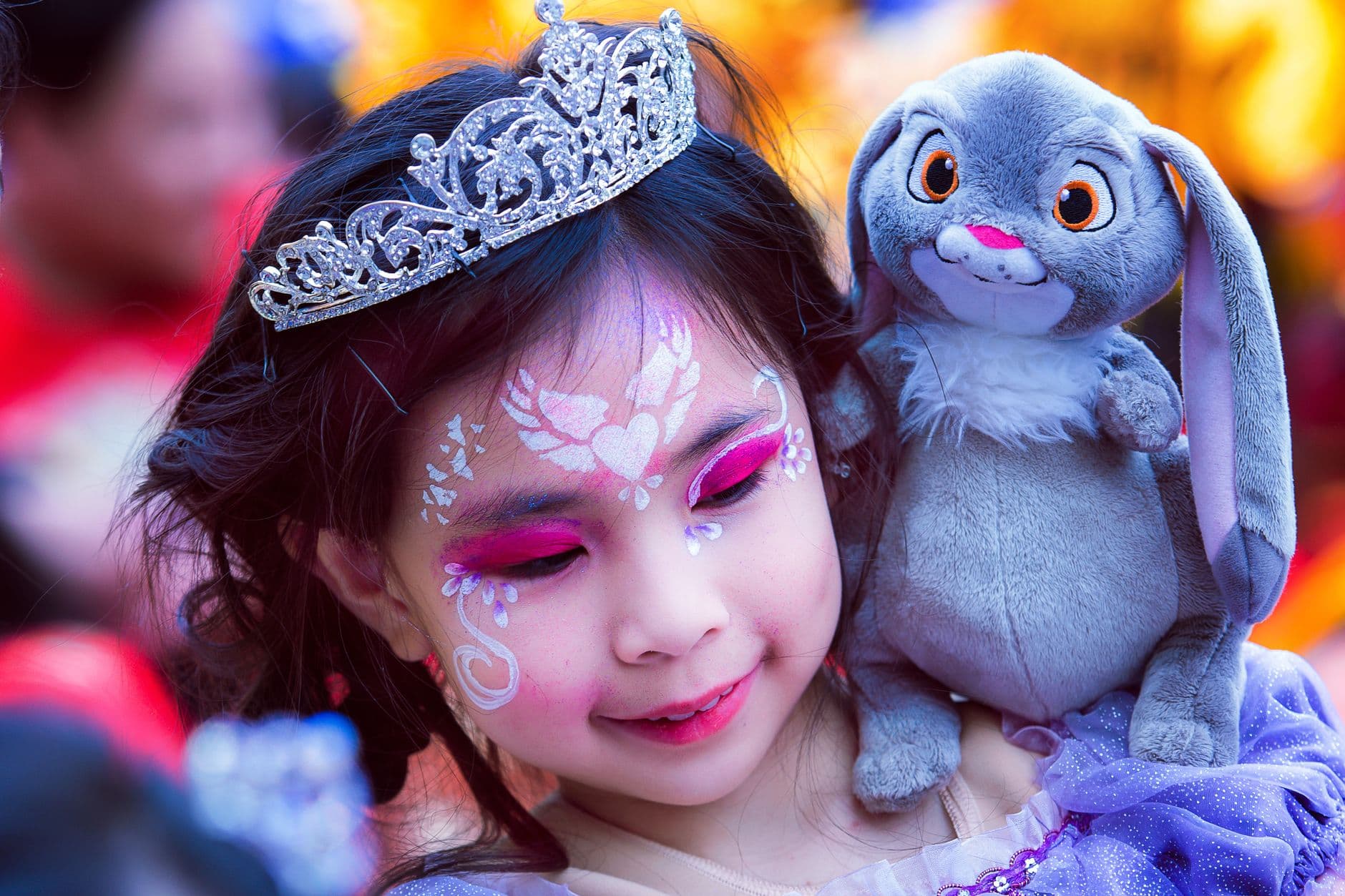 Portrait of girl with crown on head and beautiful body art on face looking down with smile