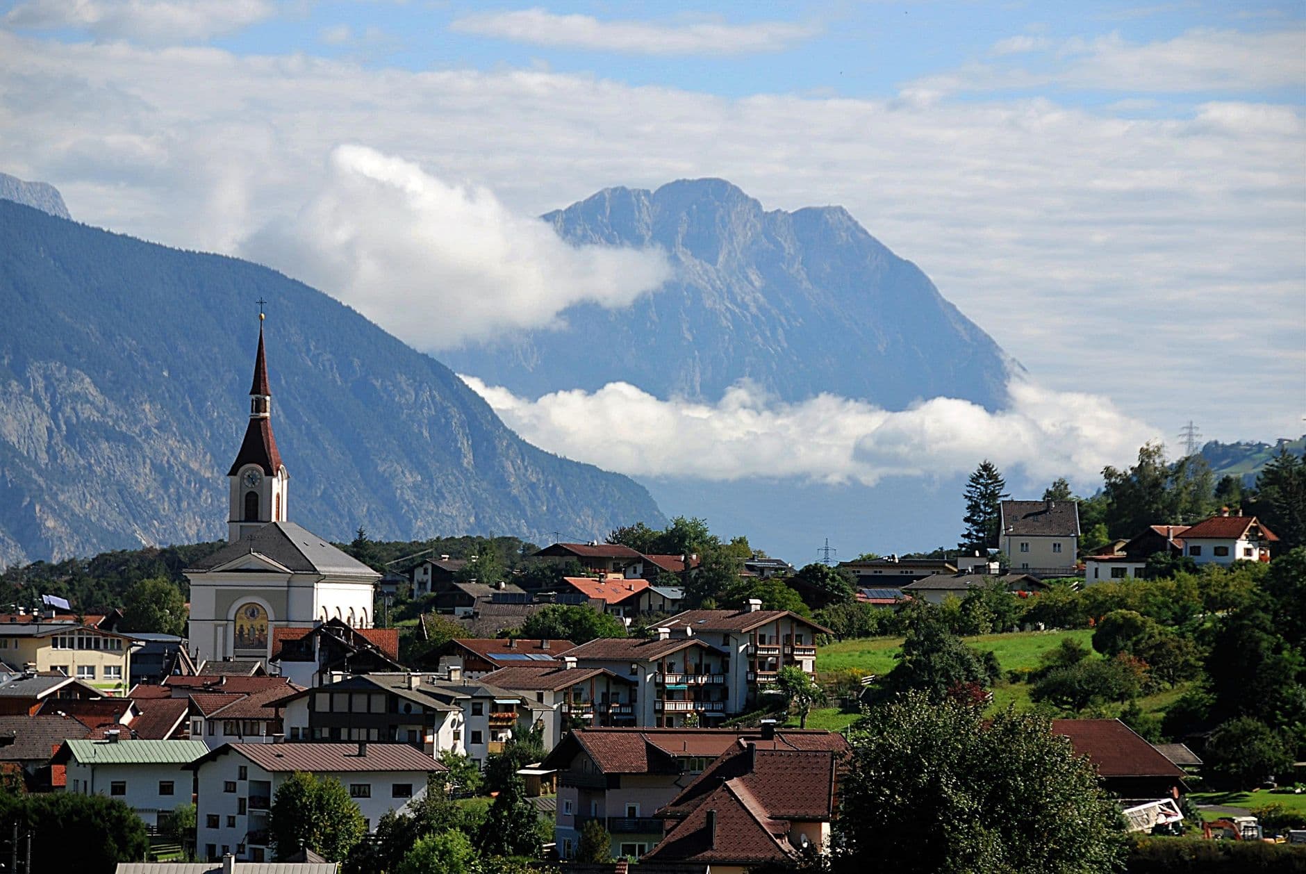 Scenic view of a picturesque Alpine village with a church, nestled against a backdrop of m