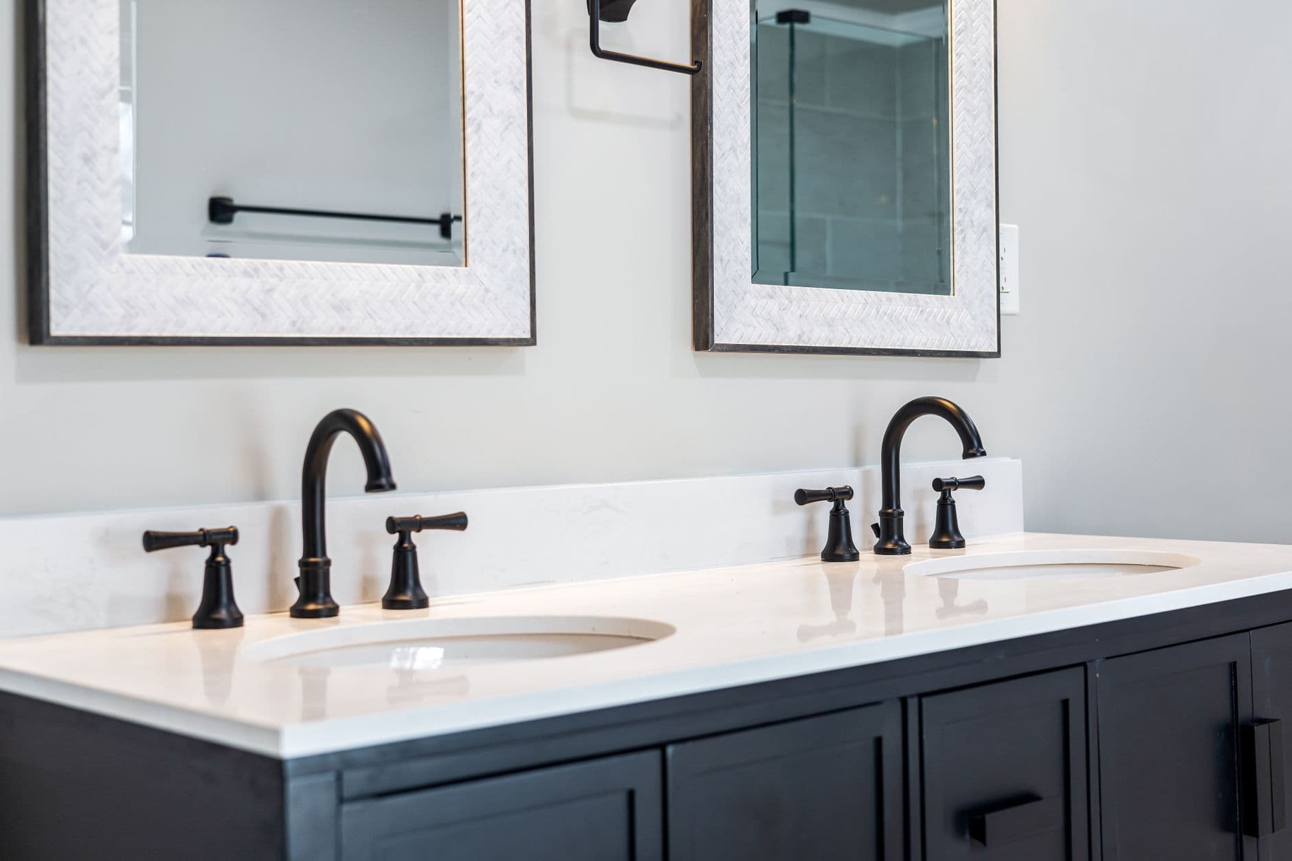 Sleek bathroom vanity featuring a double sink setup with stylish black faucets and framed