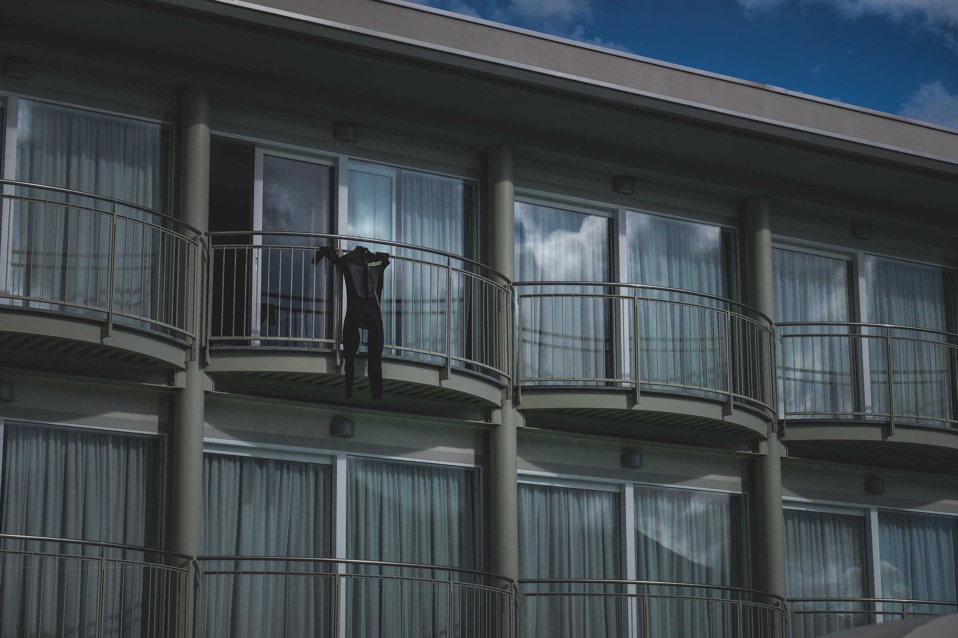 Small black jumpsuit on simple railing of balcony of modern multi storey building under bl