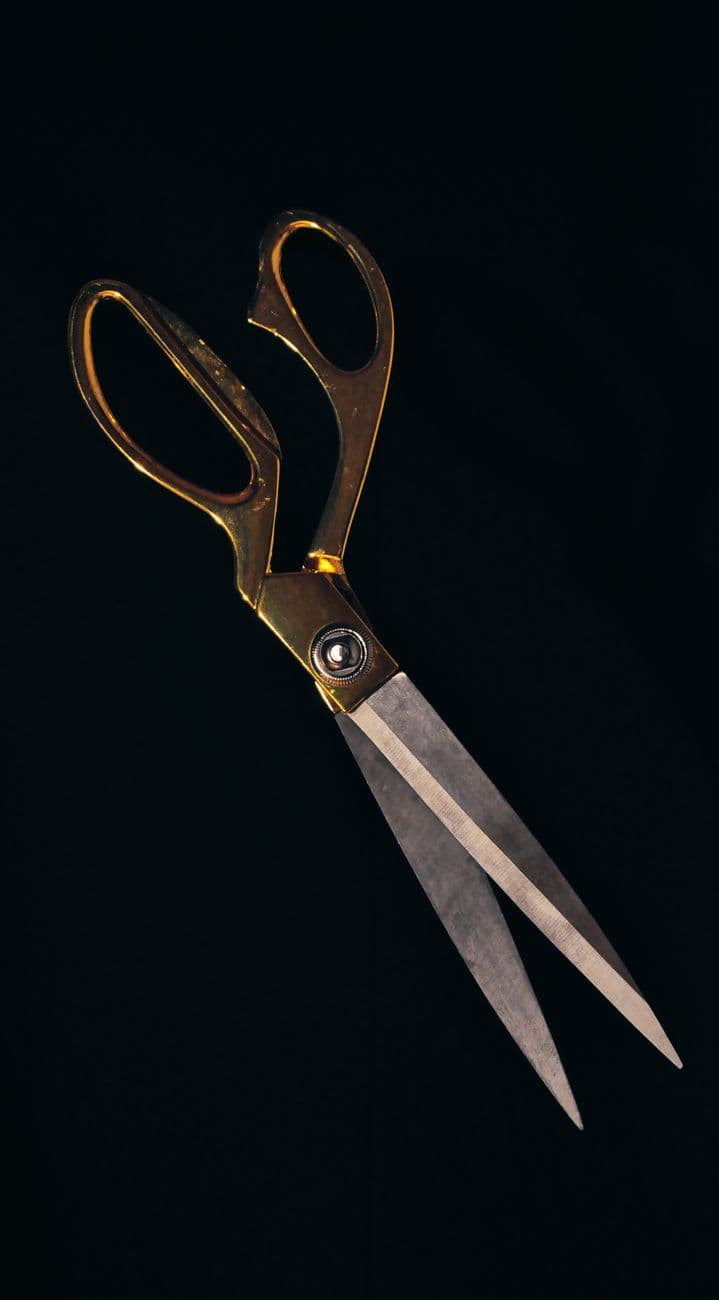 Stylish gold-handled scissors with sharp steel blades on a black backdrop, perfect for cra