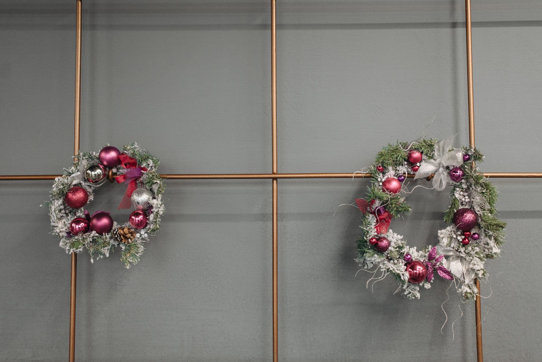 Two decorative Christmas wreaths with baubles on a stylish modern wall, adding festive cha