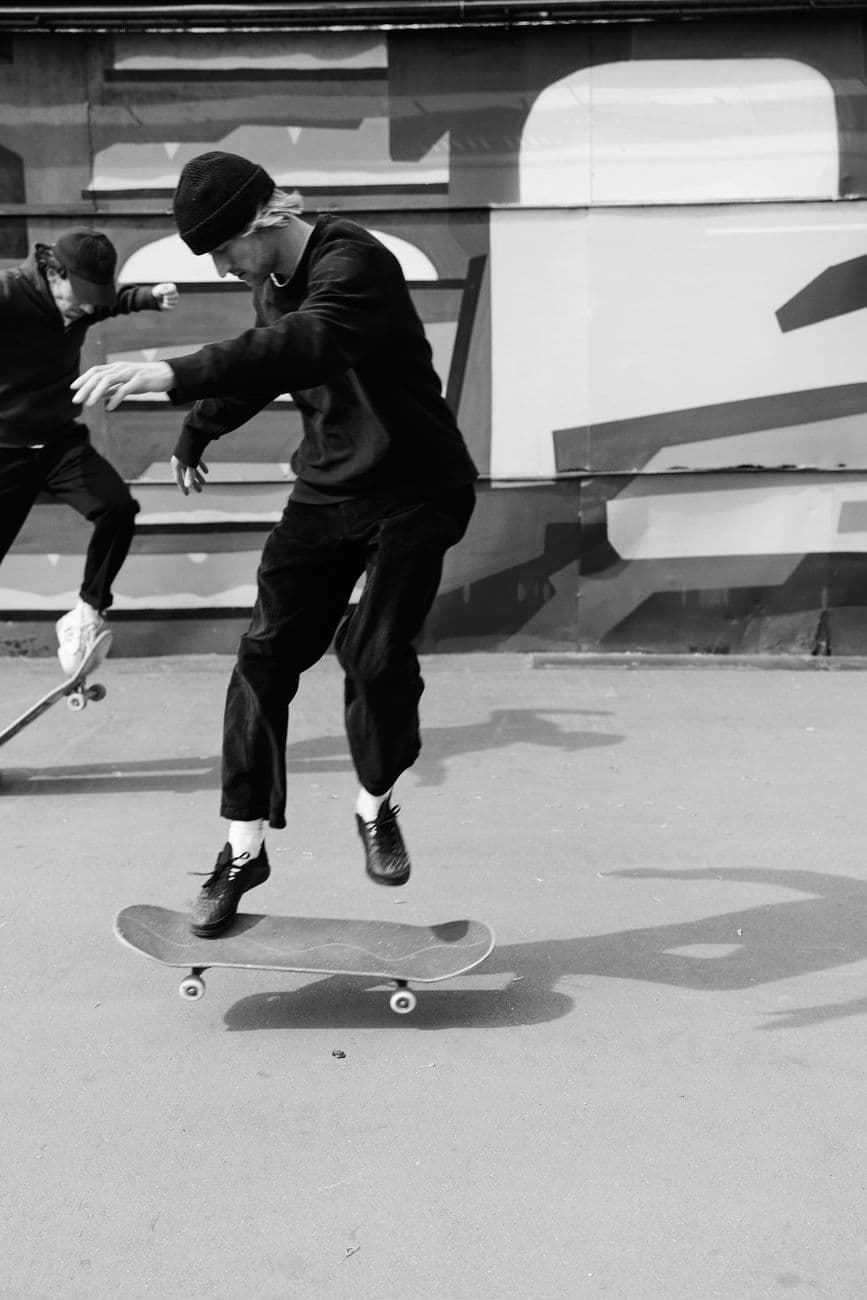 Two skateboarders performing tricks in an urban setting, captured in black and white.