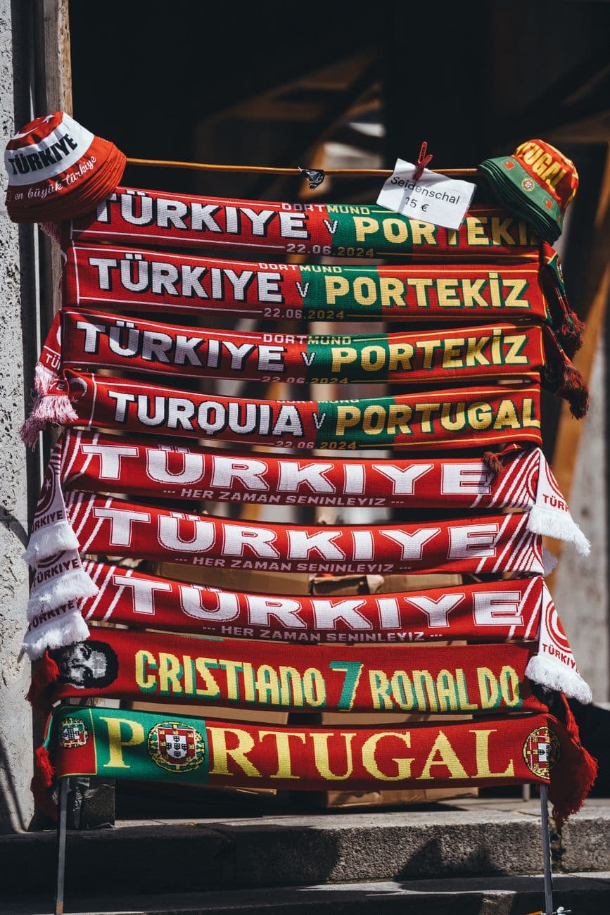 Vibrant display of football scarves featuring Turkey and Portugal teams in a local market.